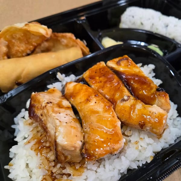 Shinrai Japanese Bistro's bento box with teriyaki salmon over rice, spring rolls, and gyoza.