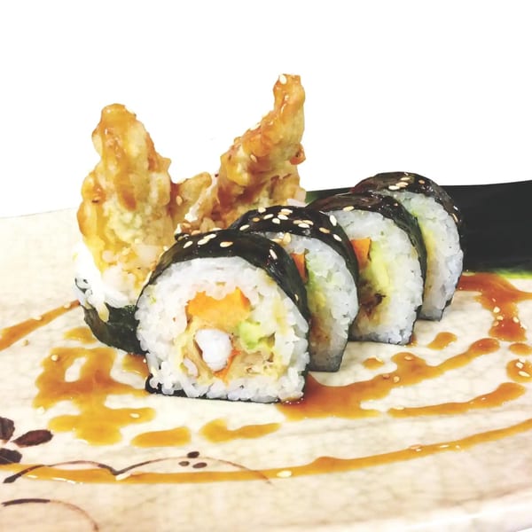 Shinrai Japanese Bistro's sushi roll with tempura shrimp, drizzled with sauce on a decorative plate.